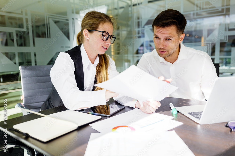 Obraz premium Collaboration in a modern office as two professionals discuss ideas while reviewing documents and sharing insights with technology on the table