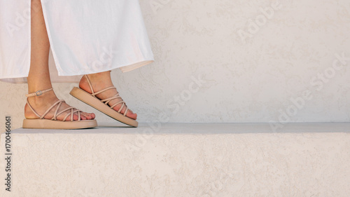 Cuadro en lienzo Woman's feet in beige sandals and white dress