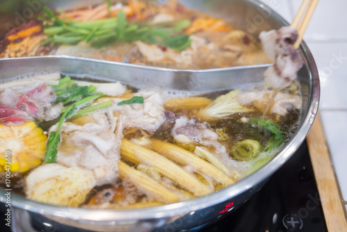 Someone using a chopsticks for pick up pork from hotpot Soup sabu