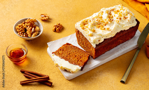 Carrot cake loaf on a white marble board. Yellow background. Close up.