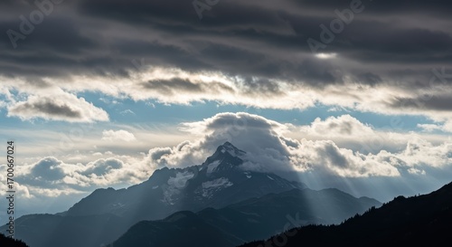 Wallpaper Mural Dramatic mountain peak emerges from a blanket of clouds, bathed in sunbeams piercing the stormy sky. Torontodigital.ca