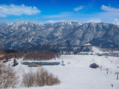 A wide ski slope with chairlifts, a restaurant and a pond at middle of Tsugaike Mountain Resort (Hakuba, Nagano, Japan)