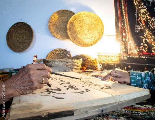 Hands crafting calligraphy on wooden board