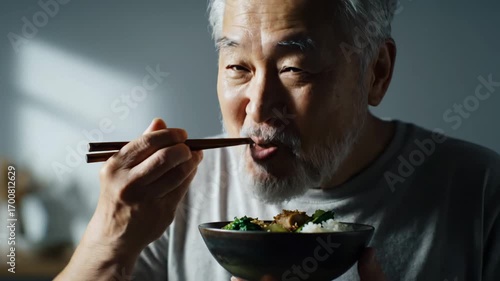 Senior asian man eats healthy food with chopsticks showing japanese cuisine this is a very happy and peaceful moment this is a great delicious meal this is a very good dinner