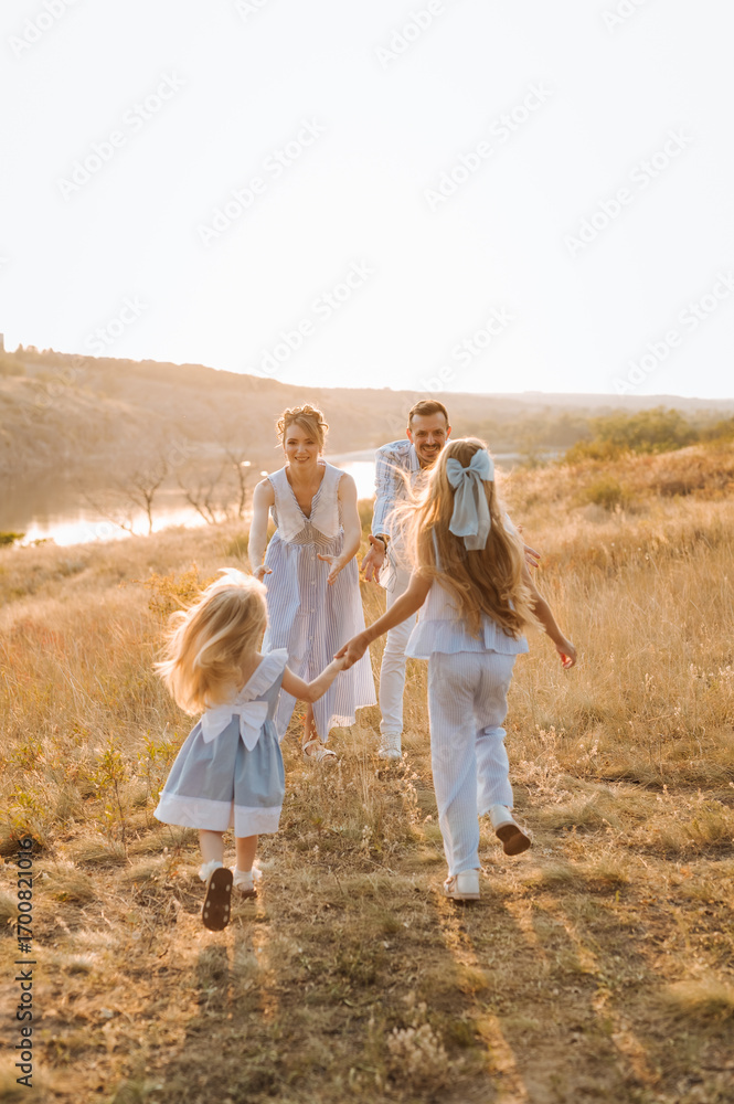 Fototapeta premium happy family having fun with two children in blue clothes on nature