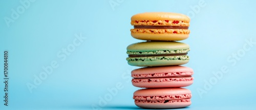 Colorful Macarons Stacked on a Light Blue Background at a Dessert Display.
