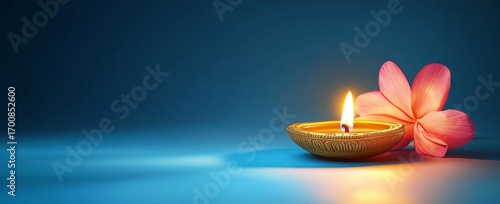Decorative Diya Lit Beside a Pink Flower on a Serene Blue Background