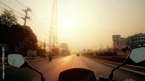 Motorcycle rider's perspective on a sunlit road during a golden hour journey