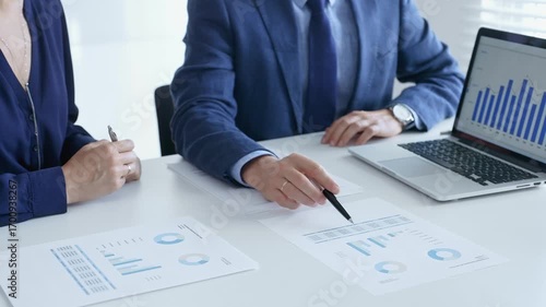 Business professionals reviewing financial data, pointing at laptop charts and shared documents during collaborative strategy session. Business people and finance concept