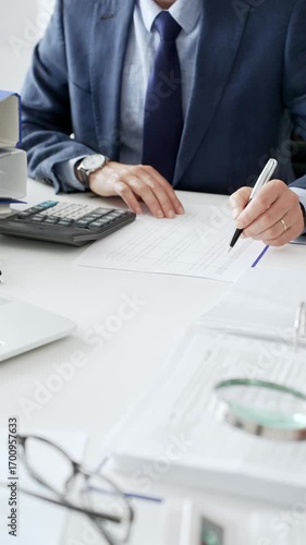 Female financial analysts with male colleague examining documents, using magnifying glass and calculator while examining corporate data at workplace in office. Audit and taxes in business