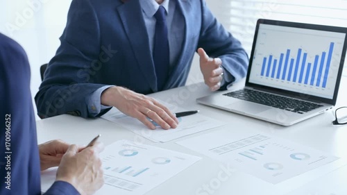 Business team of several colleagues discussing financial data on a laptop while analyzing charts and market trends in office. Businesspeople and finance concept