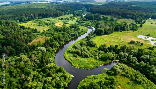 Aerial shot of a winding river carving through a lush, green landscape with forests and meadows