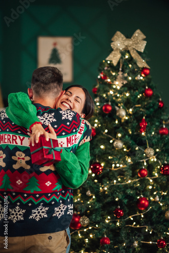 Fotografía Happy couple exchanging christmas gifts and embracing near christmas tree