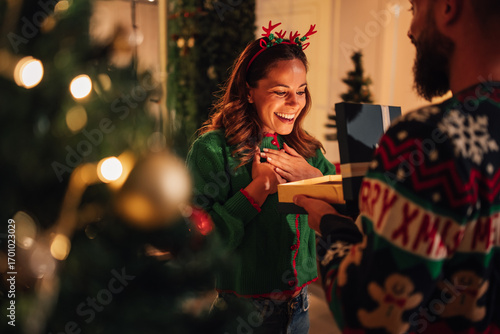 Woman receiving christmas gift and feeling surprise