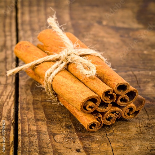 Cinnamon sticks tied with twine on rustic wood