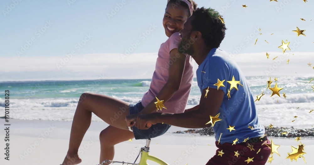 Fototapeta premium Laughing couple holding partner waist and pushing lime-green bicycle on beach, with star confetti
