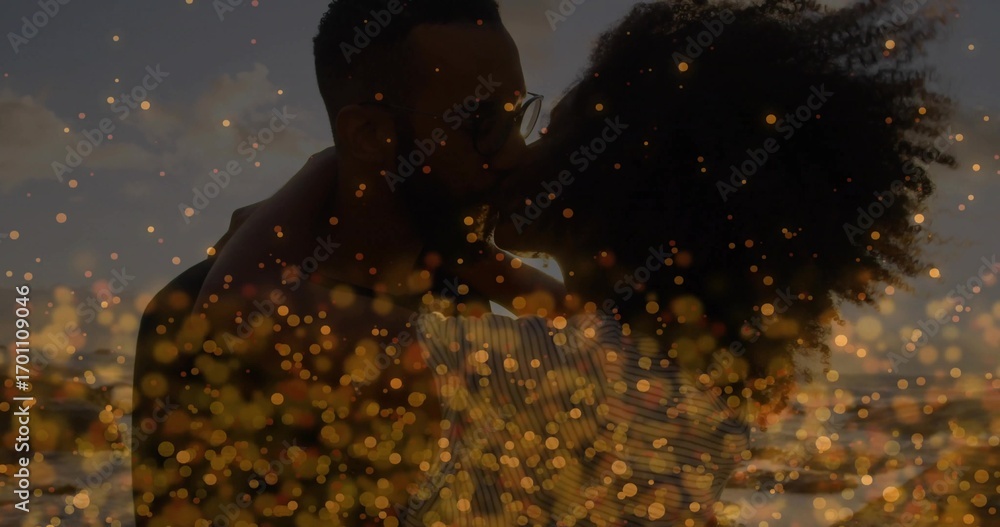 Fototapeta premium Embracing couple wearing striped top, dark shirt with eyeglasses on beach at sunset, bokeh effect