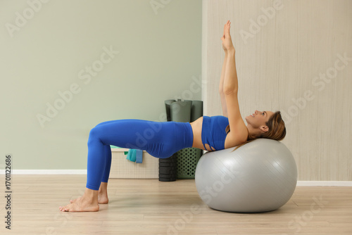 Fit woman exercising on stability ball in blue activewear