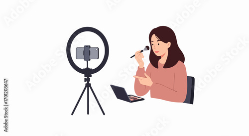 Young woman creating a beauty tutorial online, applying makeup in front of a ring light with a smartphone camera, illustrating social media content creation.