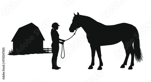 a rider stands beside horse near barn in silhouette