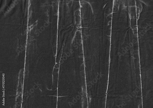 Creased black paper texture background. Monochrome crumpled grunge paper graphic element. Folded surface with abstract lines for overlay design.
