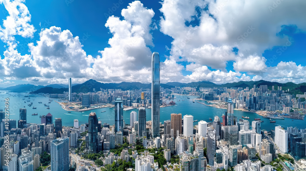 Obraz premium Aerial view of vibrant metropolis with skyscrapers, water, and mountains under blue sky