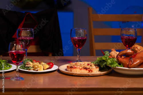 A cozy dinner table set with vibrant dishes, red wine glasses, and warm lighting, symbolizing togetherness, comfort, and the joy of sharing delicious food in a relaxed, festive atmosphere, no people.