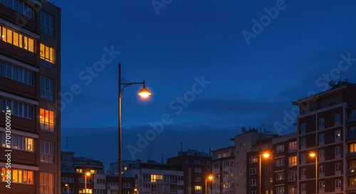 Cityscape at twilight with illuminated apartment buildings and streetlamps