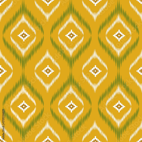 Geometric ikat pattern with diamond motifs in green and white on a warm yellow background, creating a bold and traditional textile design.