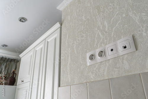 close-up shot of wall sockets and a cabinet in a room with patterned wallpaper