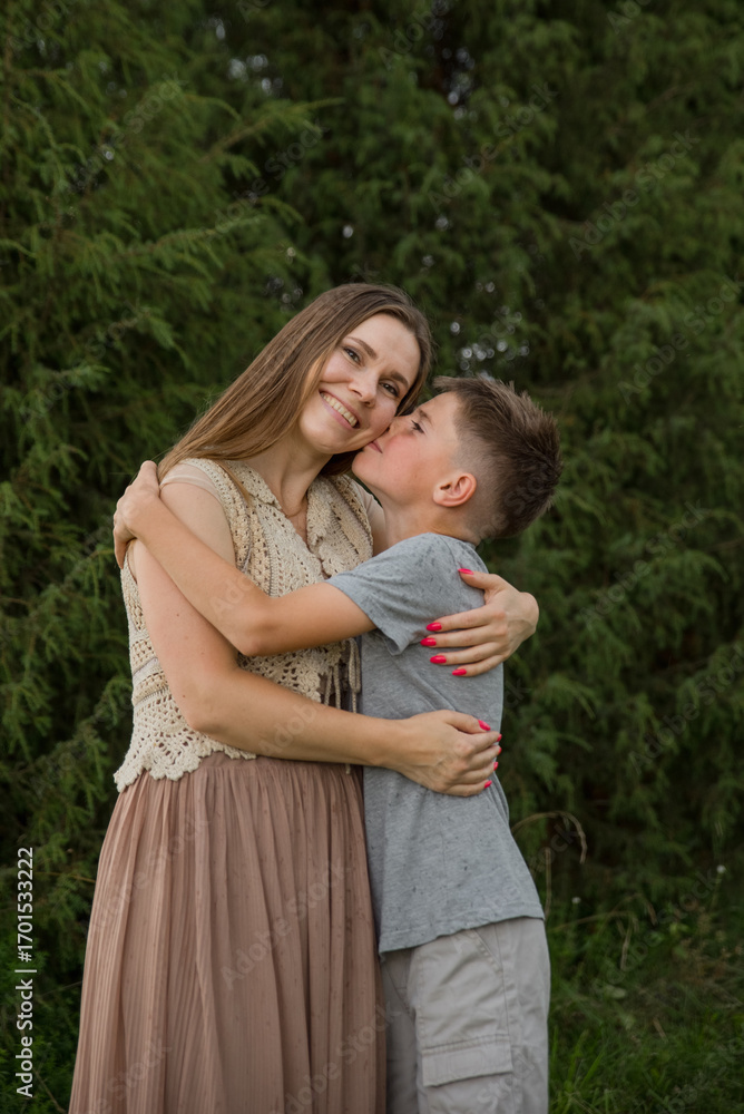 Fototapeta premium A loving son kisses his happy mother on the cheek. The concept of family, the relationship between mother and son