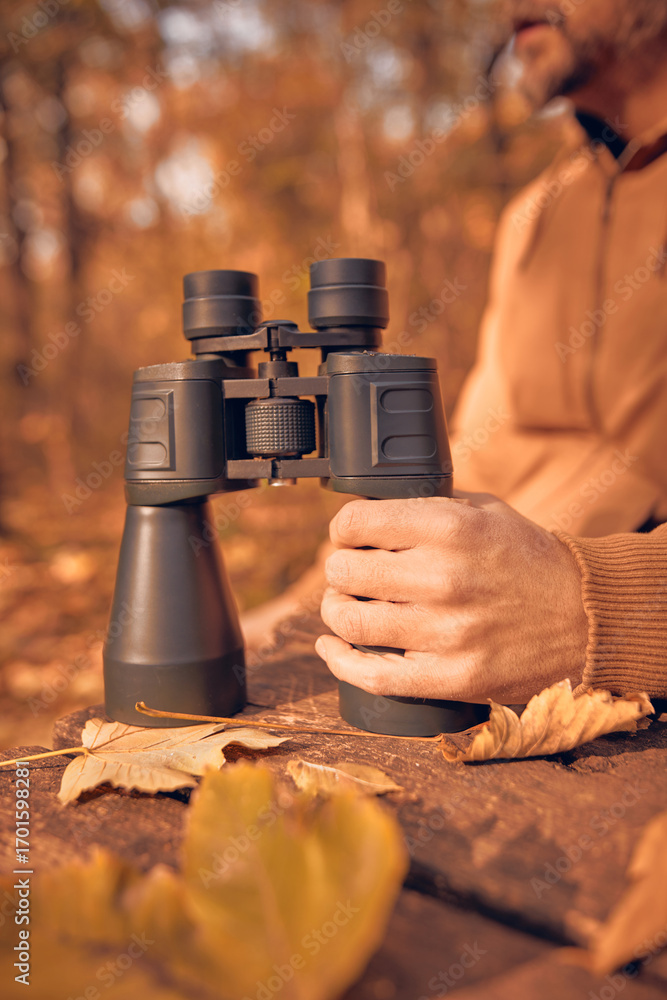 Fototapeta premium Amateur birdwatcher observing birds and other animals in nature with binoculars.