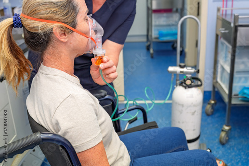 woman in wheelchair with oxygen nebuliser mask being applied by nurse, gp general practice medical healthcare clinic, asthma COPD treatment