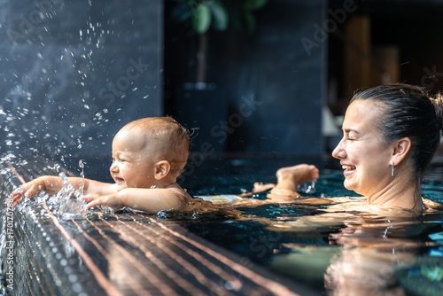 Baby splashing by spa pool edge. Fun sensory play.