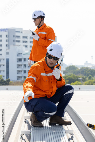 Engineers inspecting rooftop solar panels with safety gear