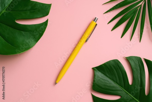 Yellow Pen on Pink Desk with Tropical Leaves