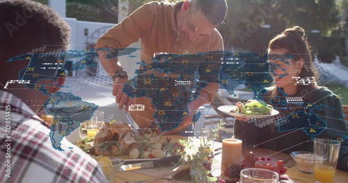 Host carving turkey sharing meal initiating animated tech map overlay while friends sipping juice