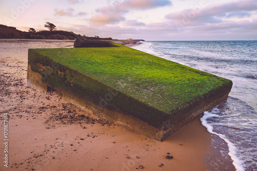 Old abandoned and partially sunken pillbox on Kessingland beach with a moss covered roof