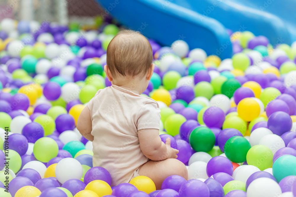 Obraz premium Baby sitting in colorful plastic ball pit. Early development