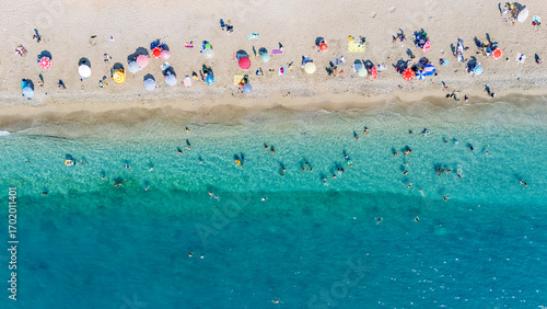Aerial drone view of sandy beach and turquoise sea waves with people sunbathing, swimming and relaxing, holiday vacation concept, Antalya Konyaalti beach, Turkey