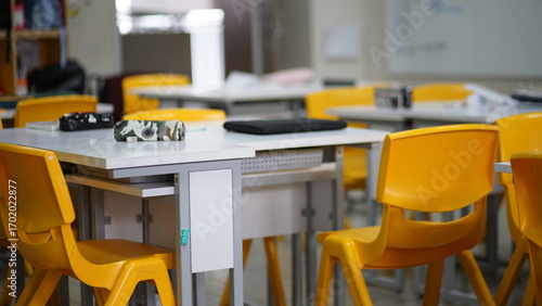 Canvas-taulu An empty classroom filled with yellow chairs and tables ready for learning