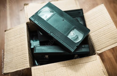 An old box with retro video cassettes on a floor.