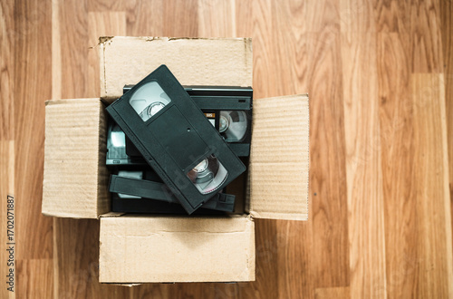 An old box with retro video cassettes on a floor.