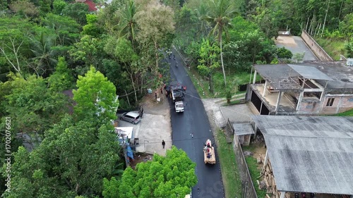 Aerial view of asphalt road repair with trial compaction process, testing surface quality before final paving. Infrastructure construction footage