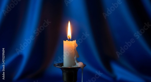 Single lit candle casting a warm glow against a blurred blue background.