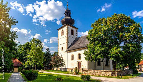 A picturesque village church stands amidst lush greenery under a vibrant summer sky.