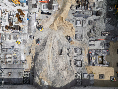 Aerial view construction site with a foundation pit of new skyscraper timelapse. Earthwork in excavation and backfilling of soil. Heavy machinery for earthmoving with crane, truck and bulldozer. 