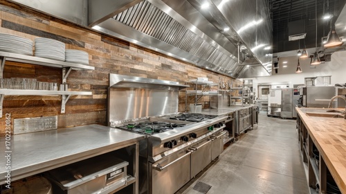 Commercial Kitchen with Stainless Steel Appliances and Wood Paneling Featuring Stove and Ventilation System
