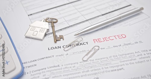 Loan contract, mortgage loan, home financing problems, debt management and rejected application : Close-up of a real video frame showing a hand stamping a red 'REJECTED' mark on a Loan Contract form.