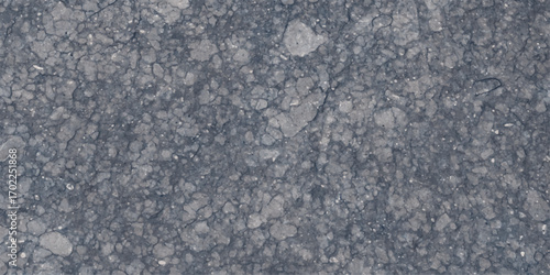 Detailed close-up texture of rough grey asphalt with visible cracks and small stones creating a natural weathered surface for backgrounds and design elements
